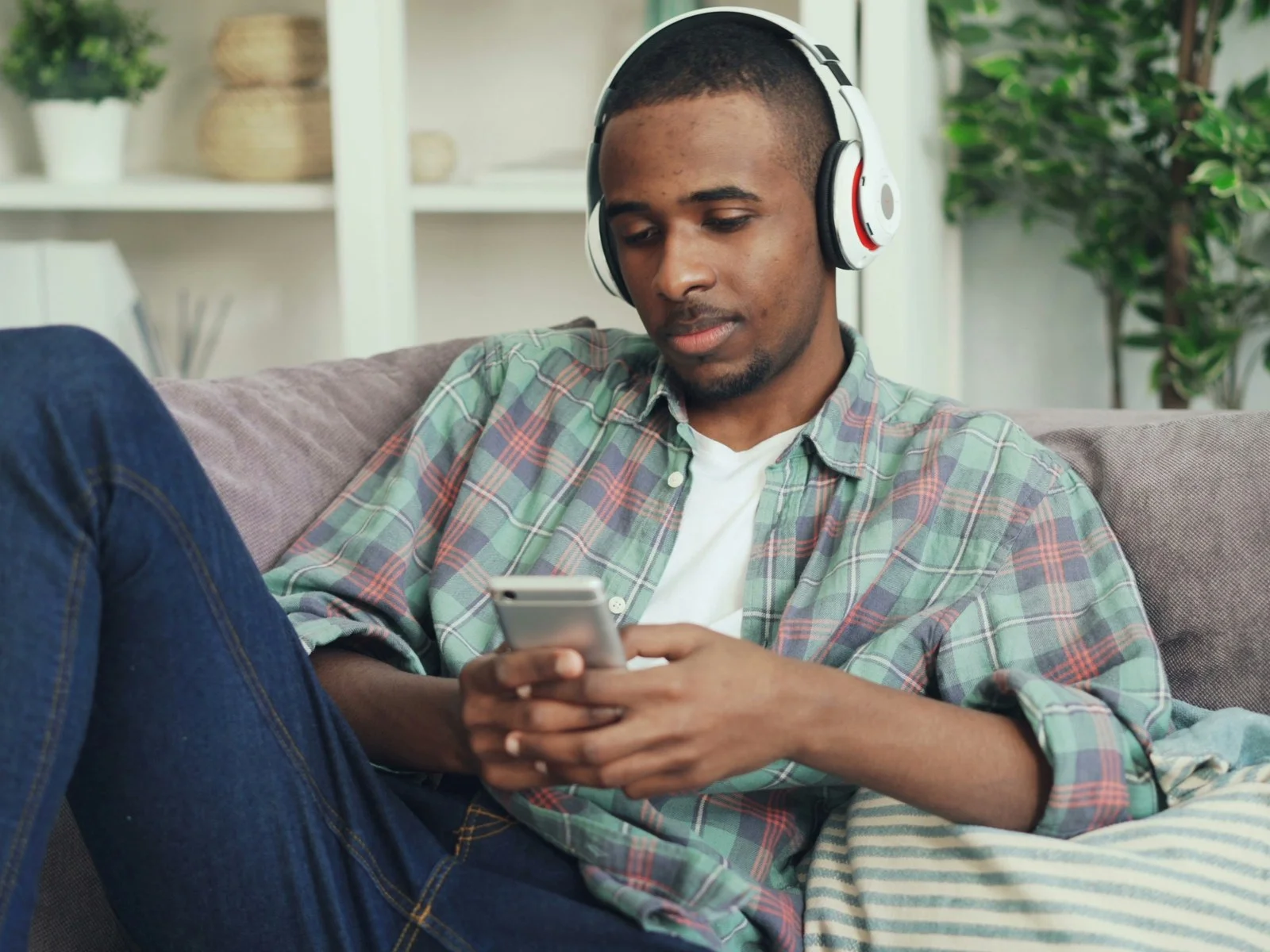 An image of a man sitting on a couch looking at his phone